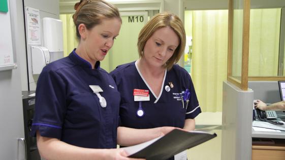 2 nurses looking at a document in a folder